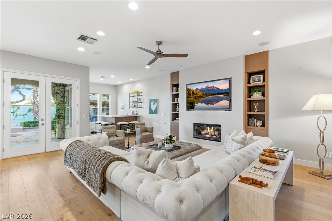 Hardwood floors and built-in shelving flank a modern fireplace in this open living area.