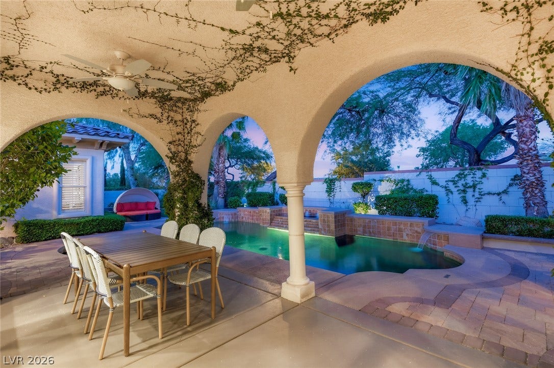 Arched columns frame views of a private swimming pool and paved patio areas.