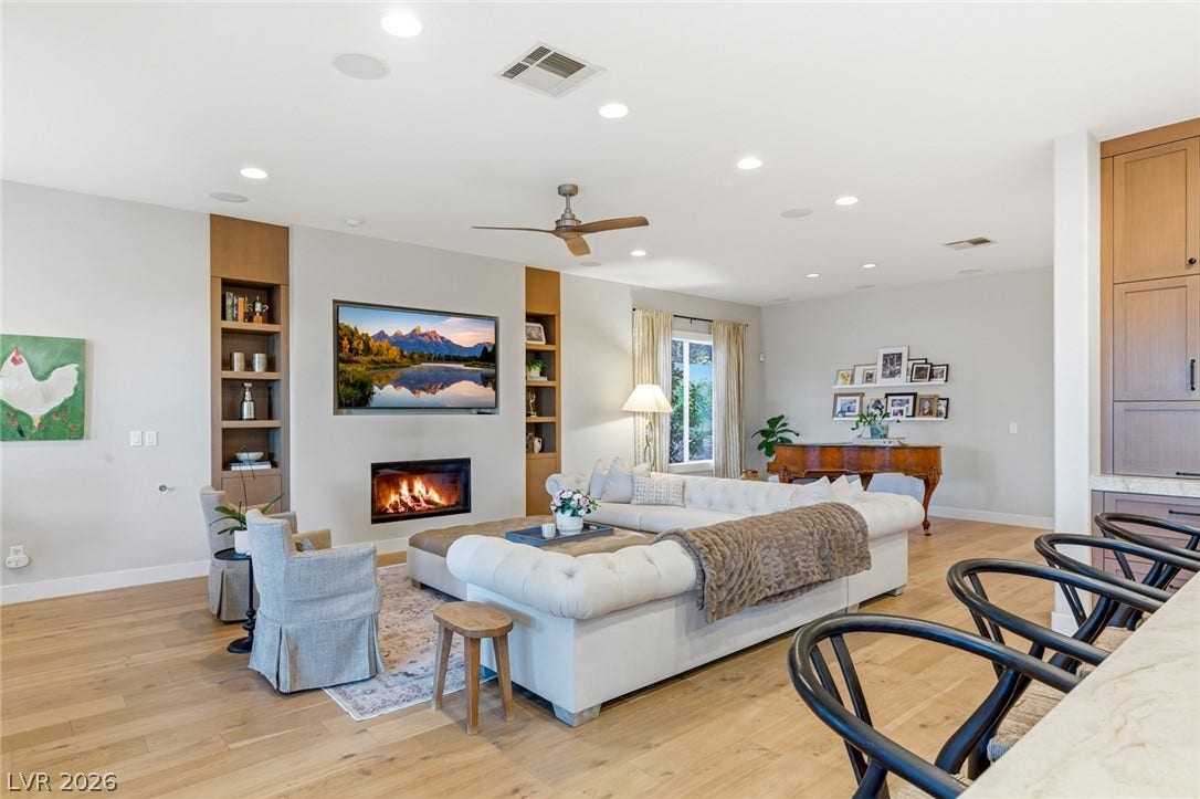 Warm hardwood floors and built-in shelving flank a modern inset fireplace.