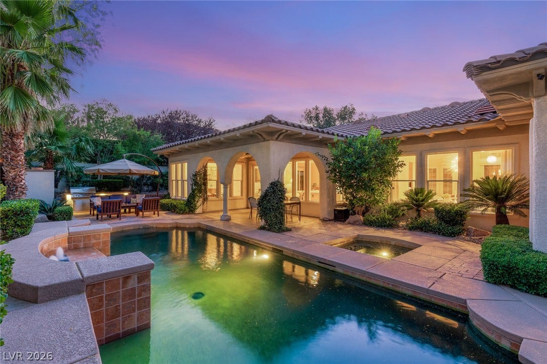 An inviting backyard oasis centers around a custom swimming pool and covered stone patio.
