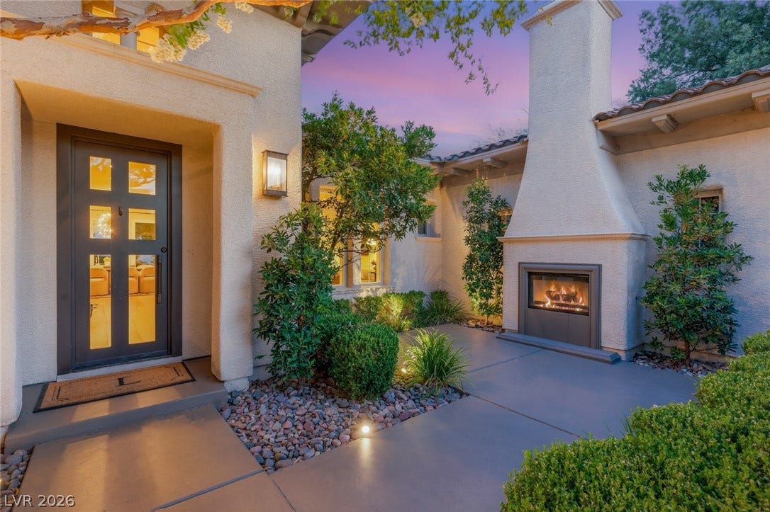 An inviting outdoor fireplace warms a charming stucco courtyard entry.