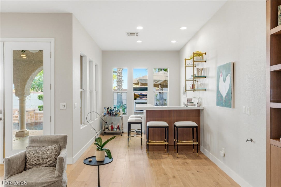 Hardwood floors and recessed lighting enhance this modern bar area designed for effortless entertaining.