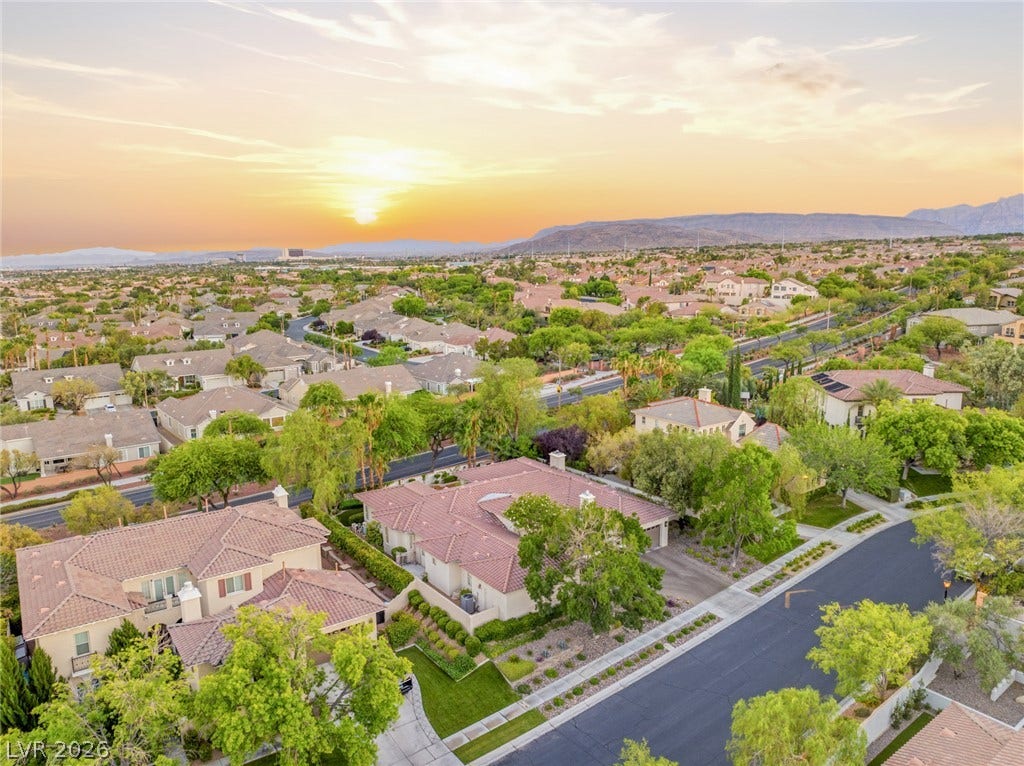 Golden sunset skies frame this neighborhood of tiled roofs nestled against a mountain backdrop.