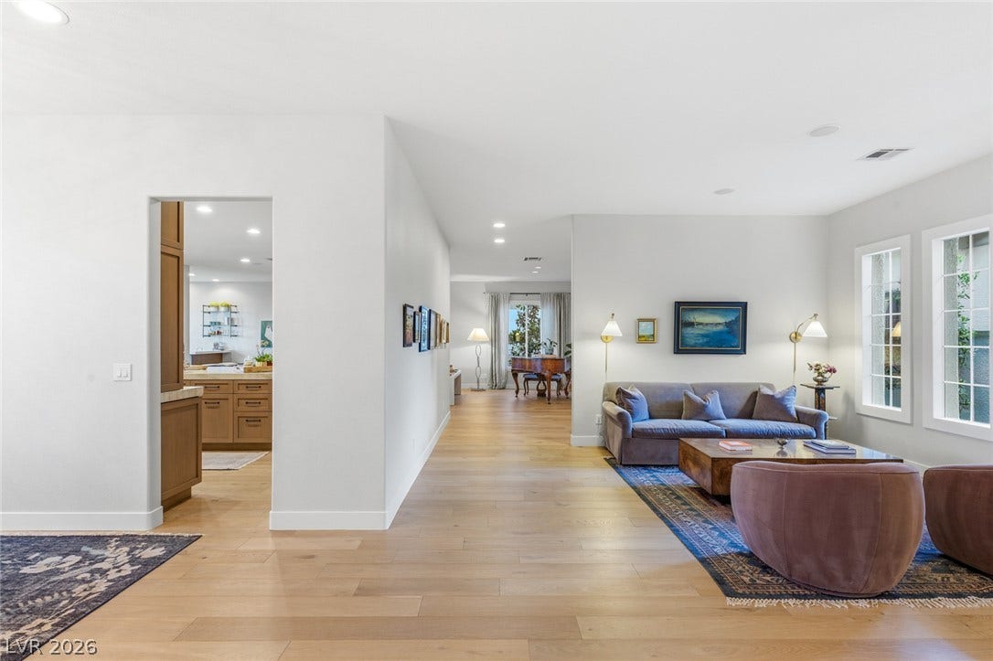 Smooth wood floors flow through this wide, light-filled interior with views into the kitchen.
