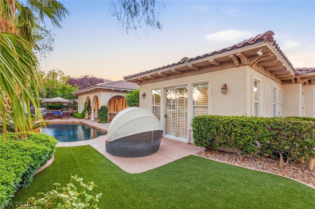 An inviting backyard oasis features a shimmering pool, manicured lawns, and classic Spanish tile roofs.