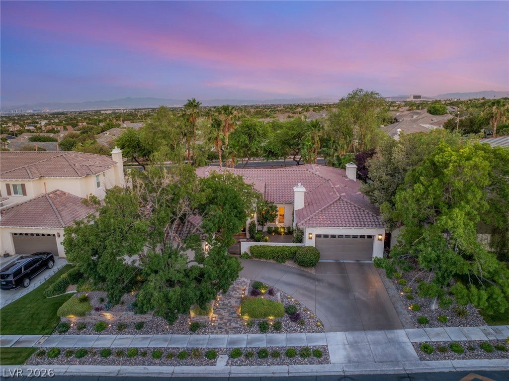 Mature trees frame a sprawling tile-roofed residence nestled within an established suburban neighborhood.