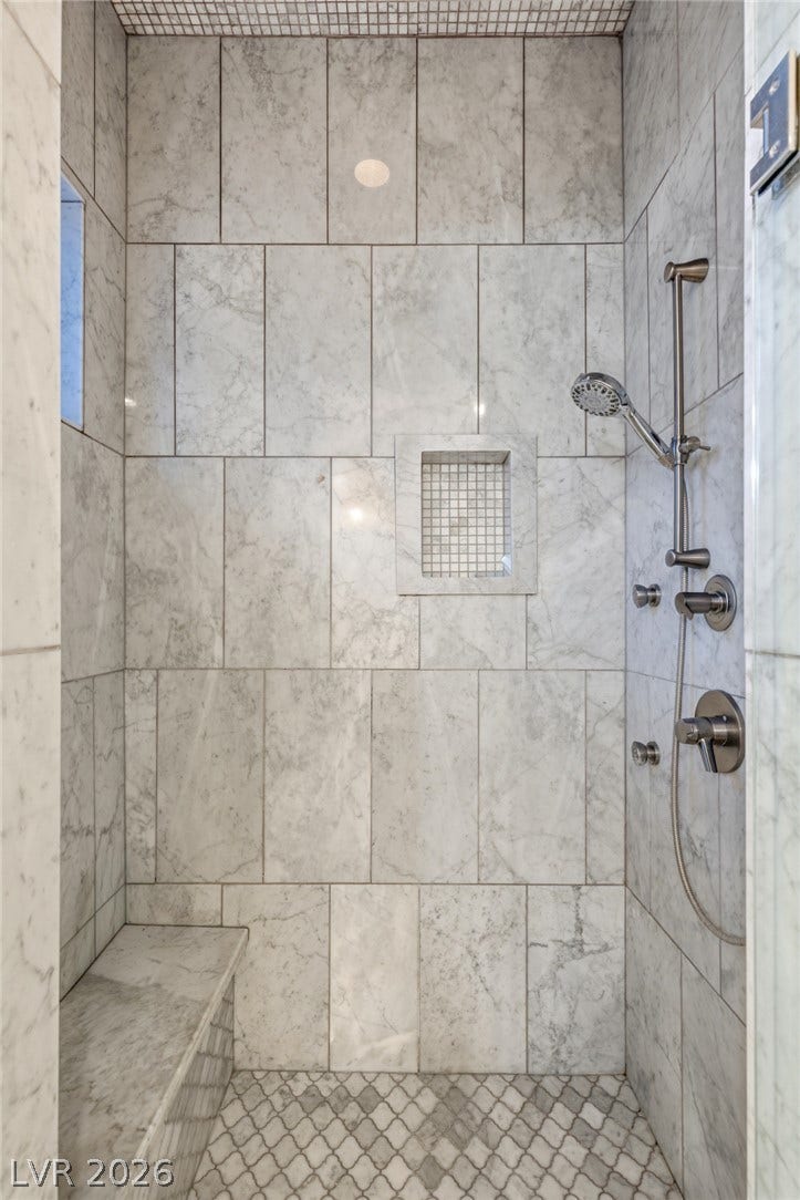 Elegantly veined marble walls line this walk-in shower featuring a built-in stone bench.