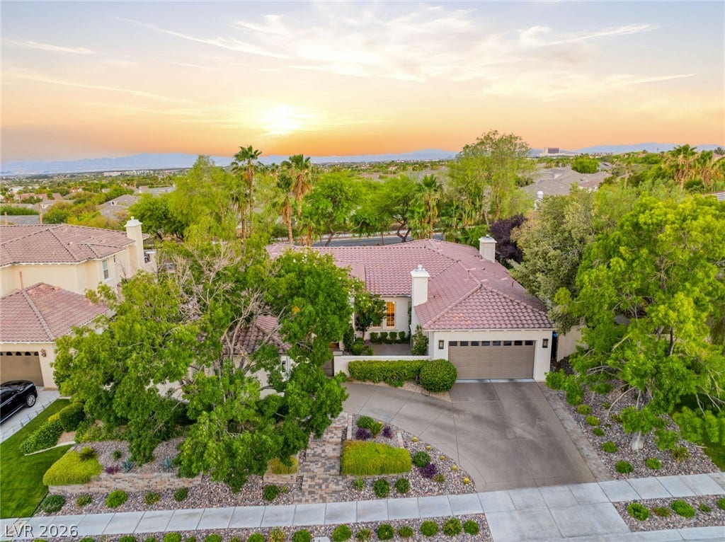A terracotta tile roof and curved driveway define this elegant home set against mountain views.