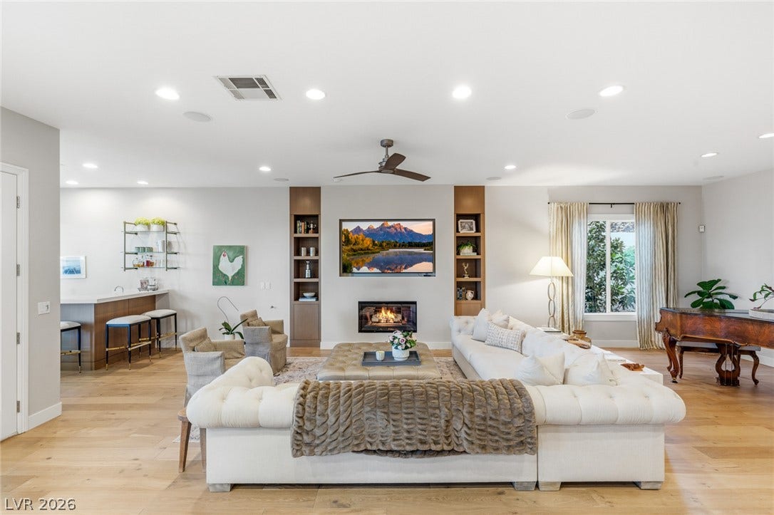 Warm wood floors and recessed lighting anchor a spacious living area featuring a modern fireplace.