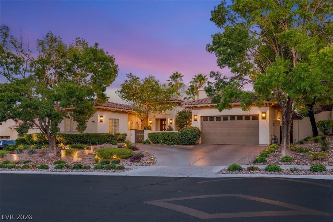 Mature trees frame the elegant stucco facade and tile roof of this inviting estate.