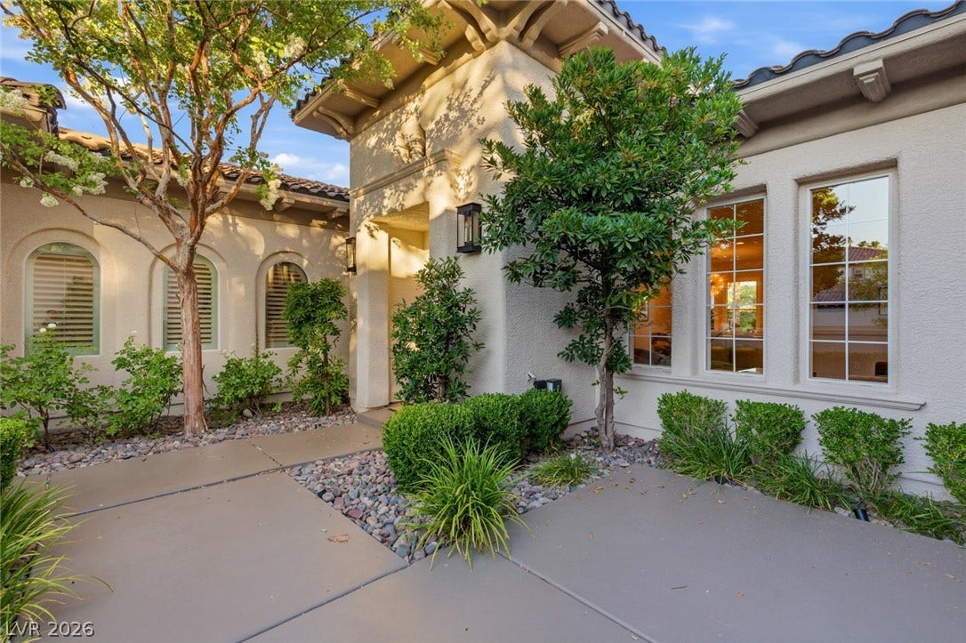 Manicured landscaping frames a welcoming entrance highlighted by grand architectural details and elegant arched windows.