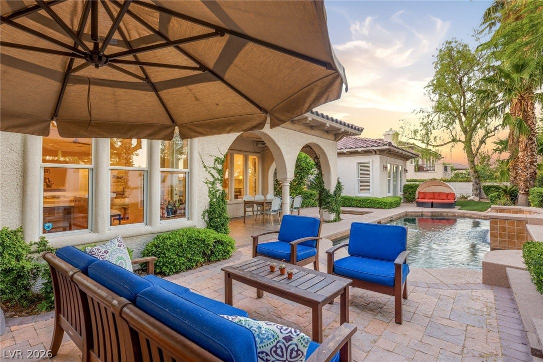 An inviting stone patio opens to a sparkling swimming pool under clear desert skies.
