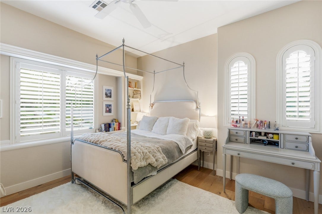 Elegant arched windows and warm hardwood flooring define this serene bedroom retreat.