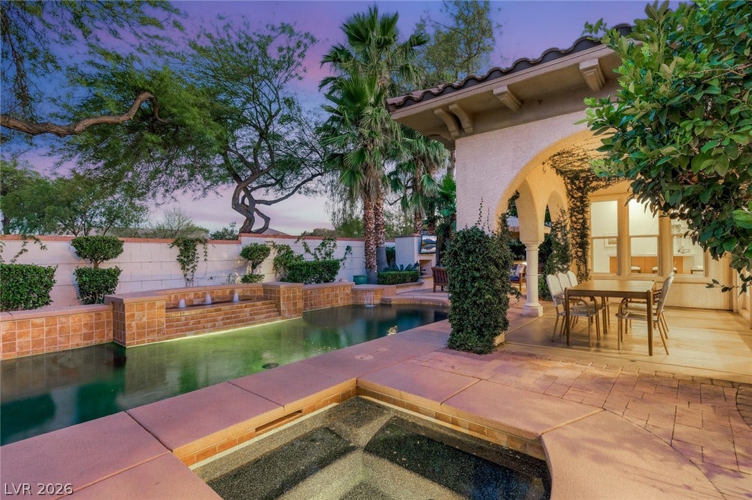 An inviting pool and spa rest alongside a covered patio with architectural arches.