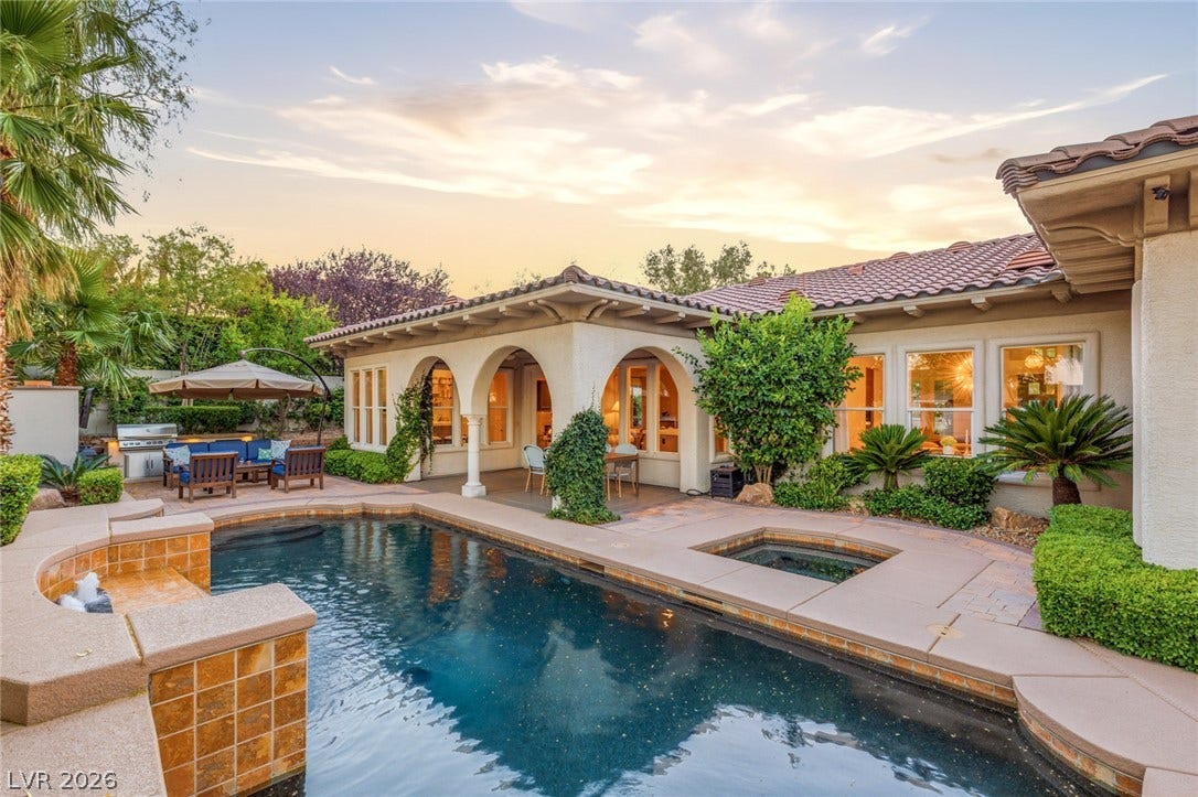 An inviting backyard oasis showcases a classic tile roof, arched loggia, and custom pool.