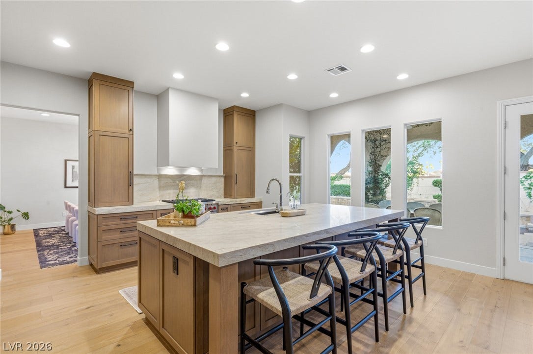 Gleaming hardwood floors and expansive windows elevate this modern kitchen featuring a grand central island.