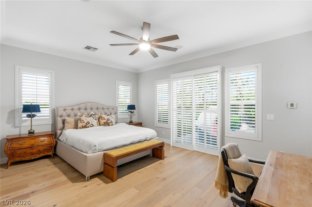 Polished hardwood floors and classic crown moldings elevate this serene, light-filled bedroom suite.