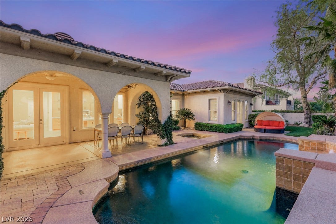 An inviting backyard oasis centers around a custom swimming pool framed by classic arched loggias.
