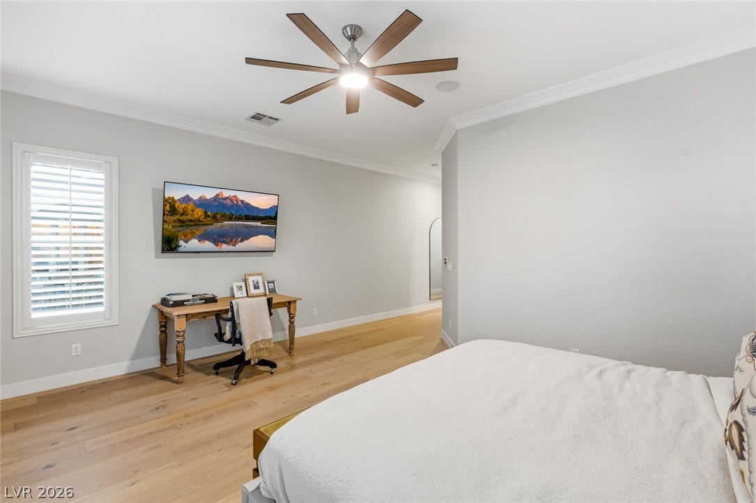 Rich hardwood flooring and elegant crown molding elevate this serene and restful bedroom retreat.