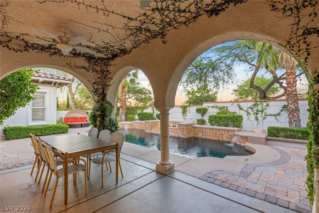 Arched columns frame views of a private swimming pool and paved patio areas.