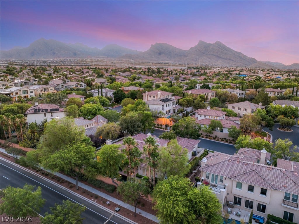 Dramatic mountain ranges frame this tranquil residential neighborhood under a colorful twilight sky.