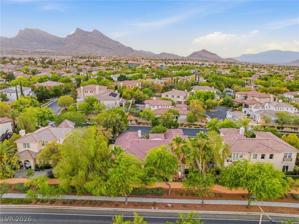 Dramatic mountain peaks rise beyond a peaceful residential neighborhood of tile-roofed homes.
