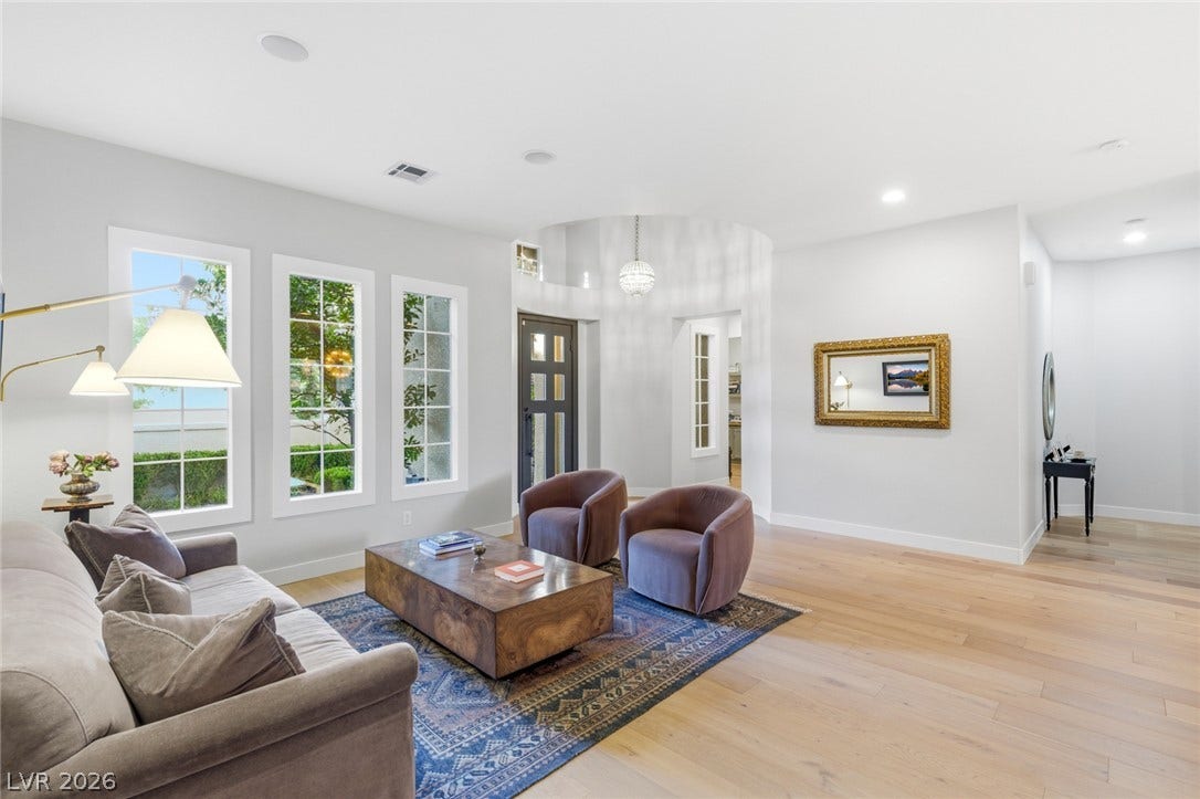 Sunlight streams through tall windows onto pristine hardwood floors in this welcoming main living area.