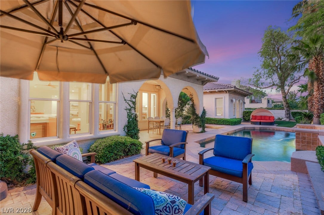 An inviting backyard oasis features a brick paver patio alongside a sparkling swimming pool.