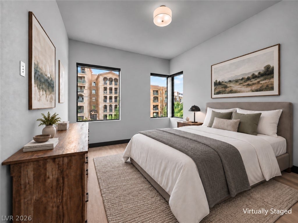 Natural light streams through large windows onto beautiful wood flooring in this serene bedroom.
