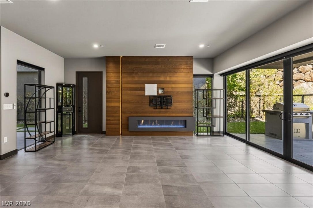 A modern linear fireplace anchors the living room, surrounded by sleek tile flooring and glass doors.
