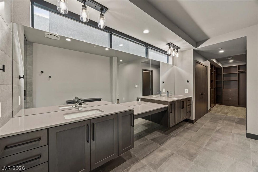 A long dual vanity highlights this clean bathroom, showcasing quartz countertops and large mirrors.