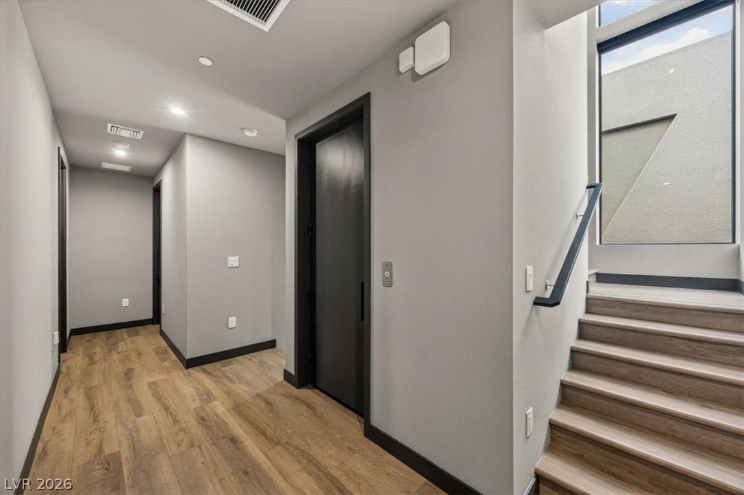 Clean lines and warm wood floors define this modern hallway, complete with private elevator access.