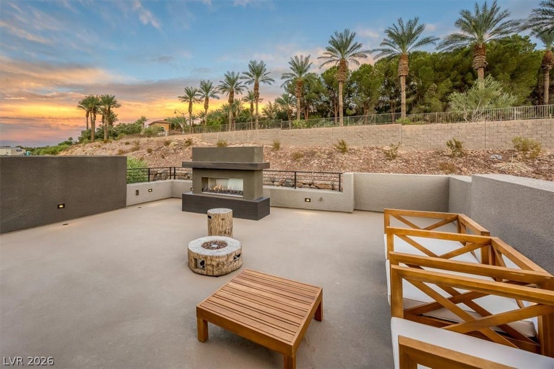 An open patio terrace showcases a built-in outdoor fireplace set against a scenic backdrop.