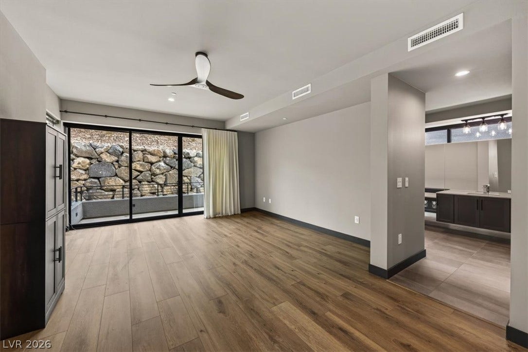 Warm wood flooring and sliding glass doors create a welcoming, airy atmosphere in this modern space.