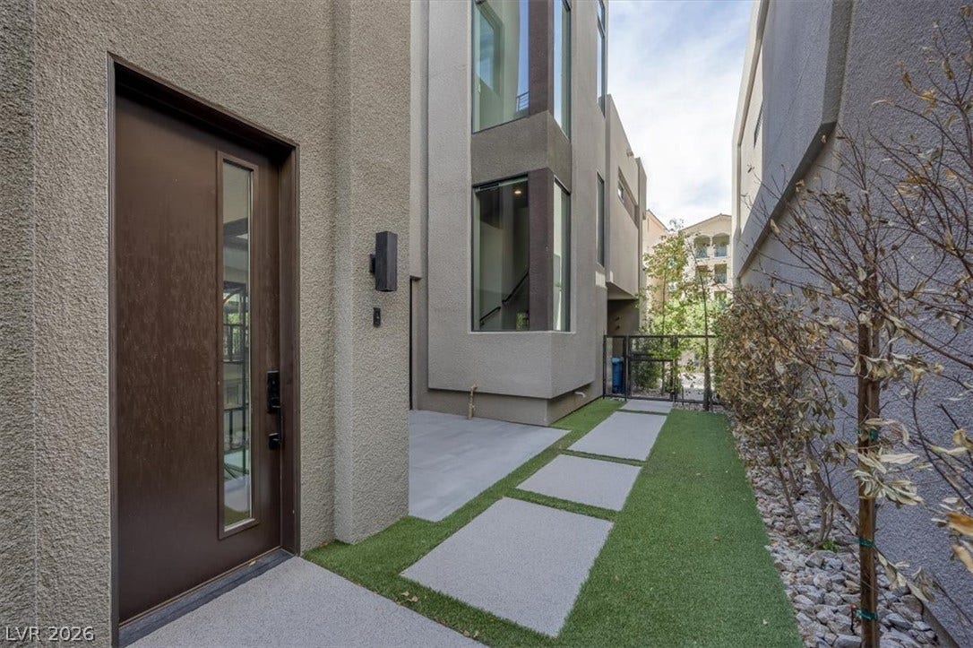 Geometric pavers and synthetic turf lead to a private, contemporary stucco entry.