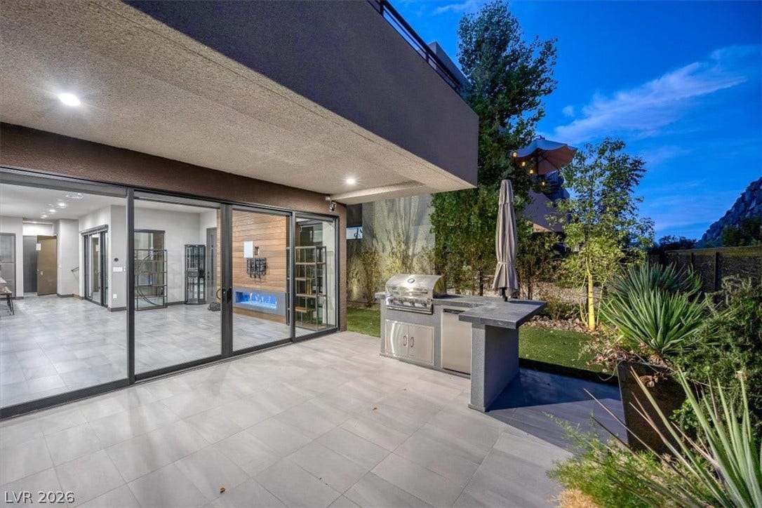 An outdoor kitchen on a tiled patio connects seamlessly with the open interior spaces.