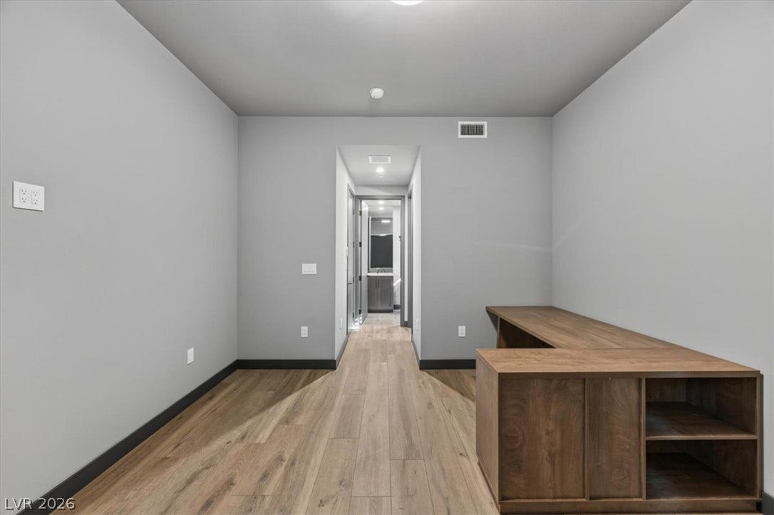 Smooth wood-look flooring stretches through this versatile space leading directly into the hallway.