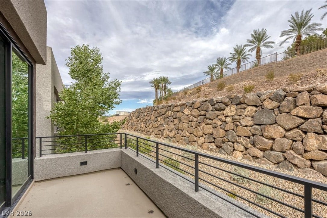 A spacious concrete balcony looks out over a massive, beautifully terraced stone retaining wall.