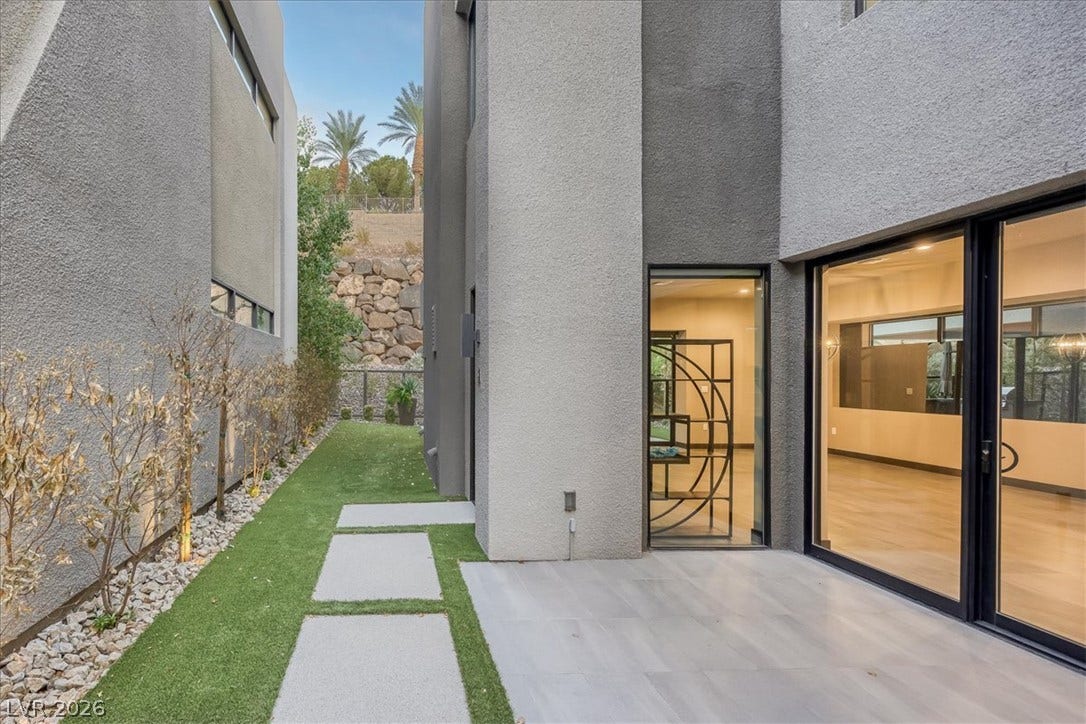 Modern stucco exteriors frame a sleek patio transitioning to a manicured side yard walk.