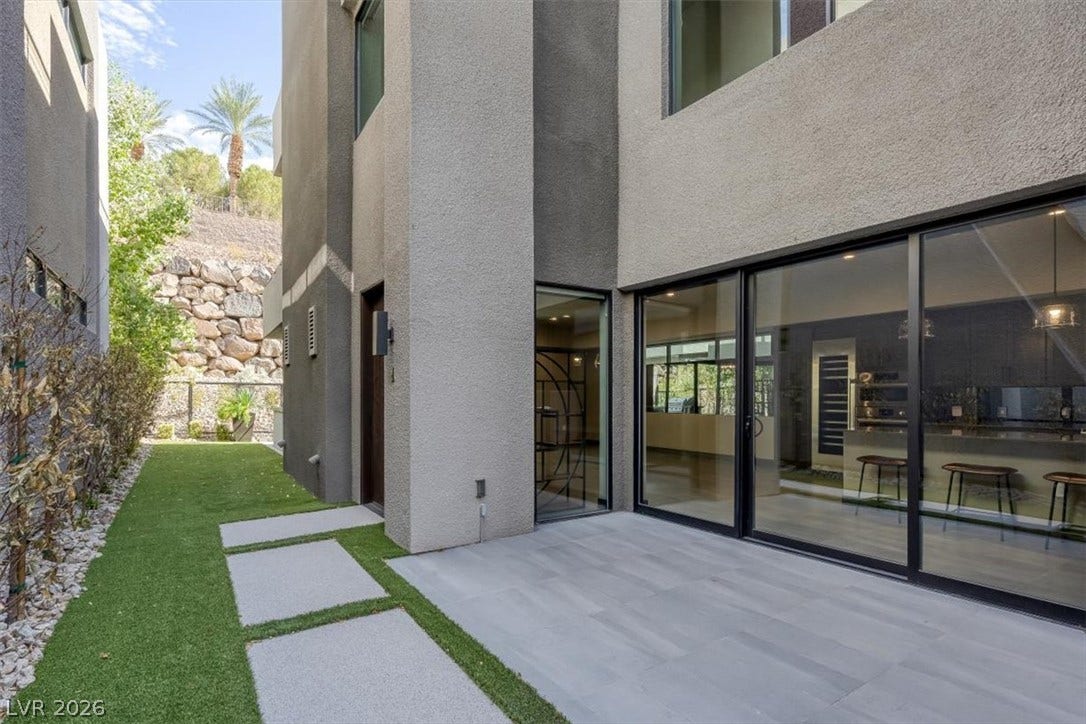 A tiled patio transitions to green lawn space along the exterior of this modern residence.