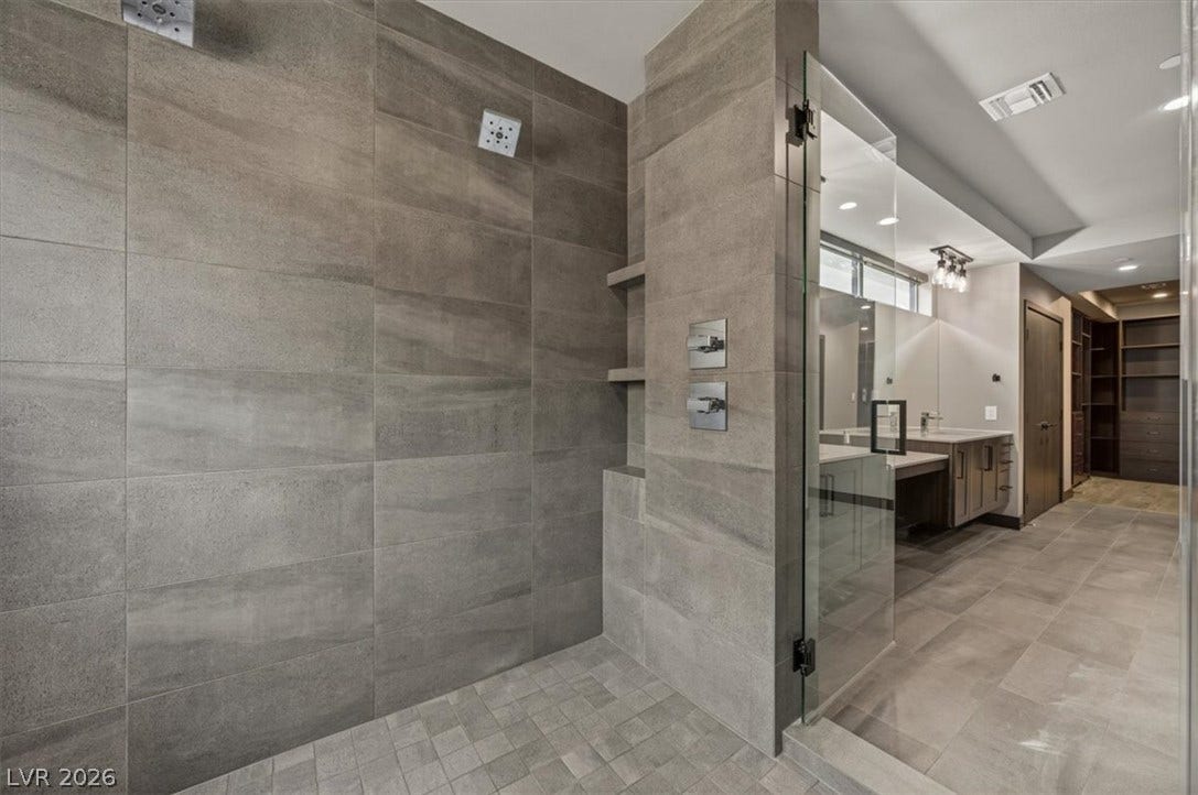 A spacious walk-in shower lined with large-format tile adjoins the main bath and closet.