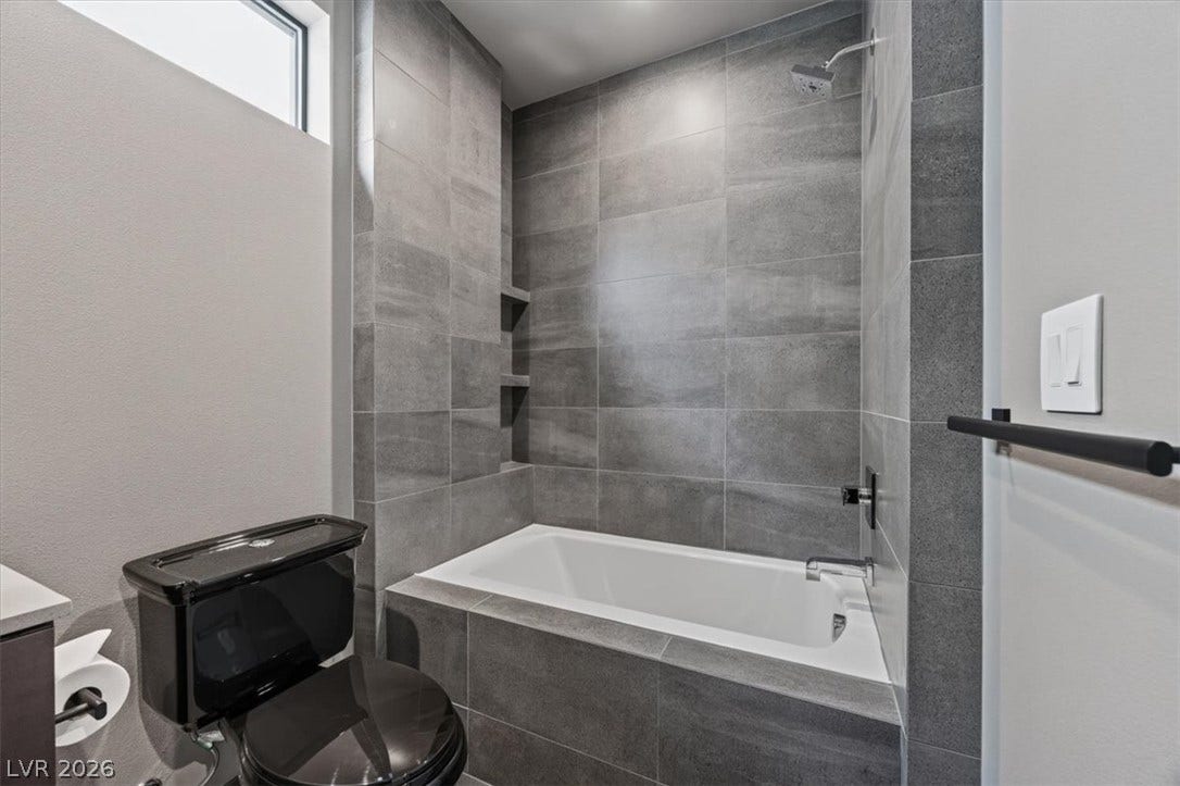 Floor-to-ceiling tiles enclose a deep soaking tub in this contemporary bathroom setup.