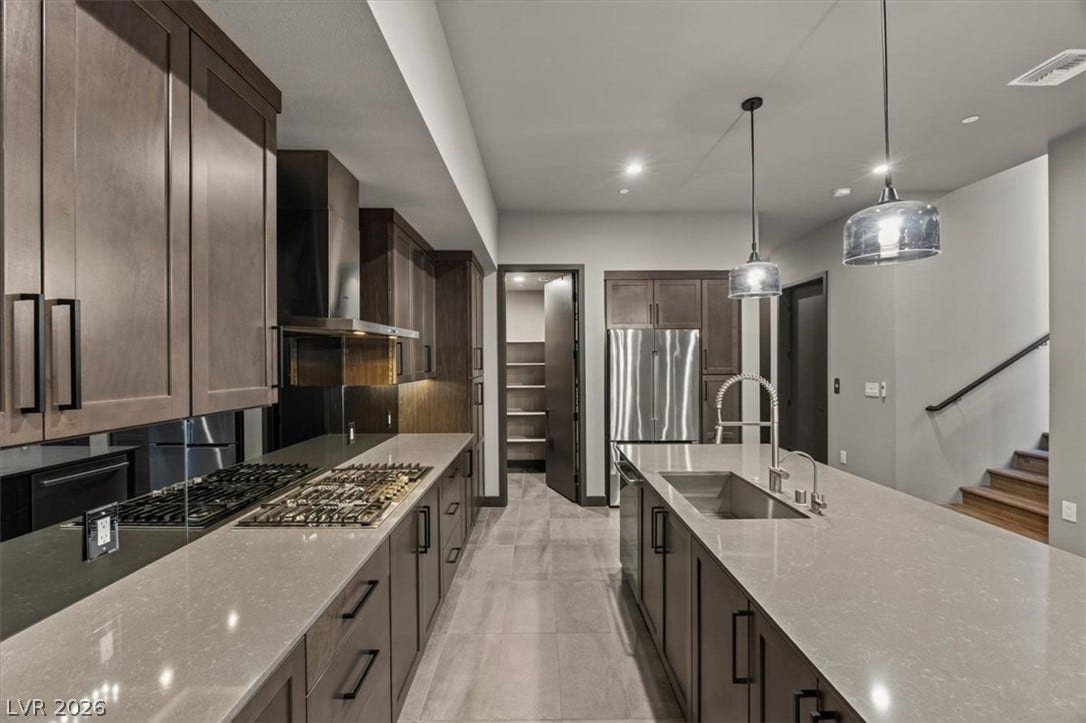 Rich dark wood cabinets frame a spacious culinary workspace with a large central island.