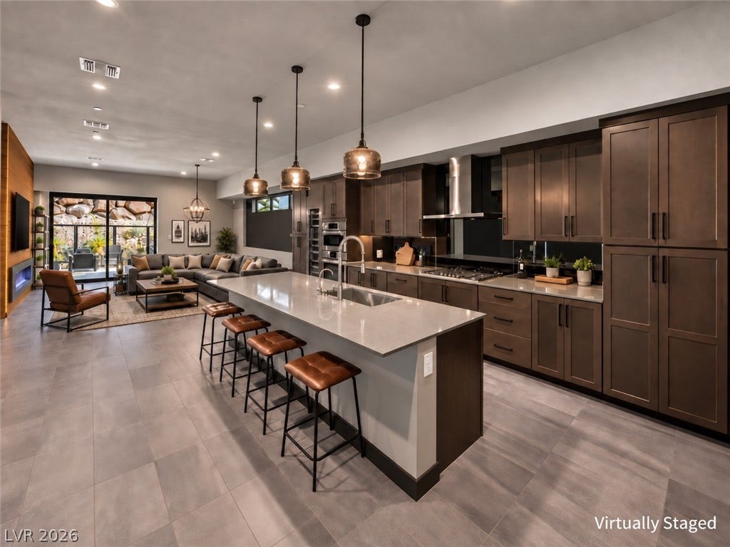 A spacious central island Anchors the open kitchen beneath recessed lighting and sleek tiled floors.