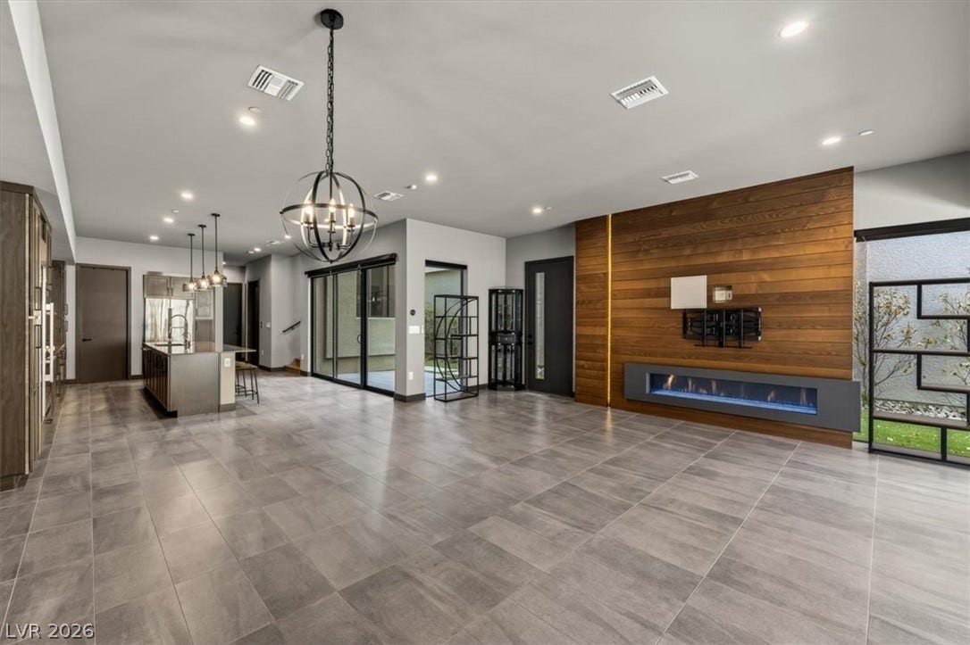 A modern fireplace set in wood paneling anchors this open-concept space featuring tile flooring.