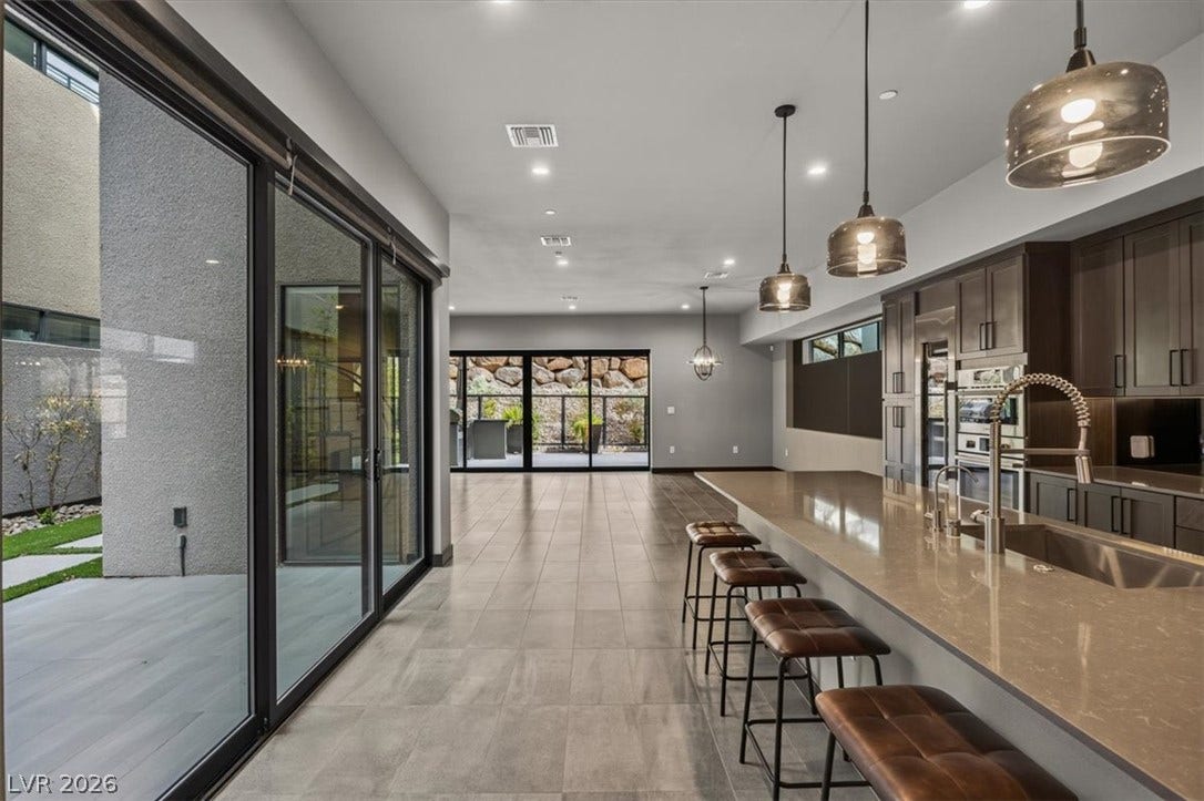 Polished tile flooring and expansive sliding glass doors define this open-concept kitchen space.