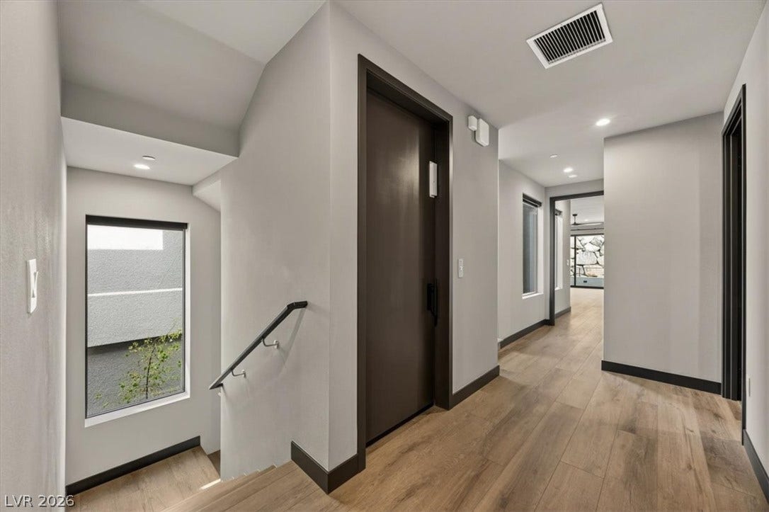 Warm wood flooring and clean architectural lines guide visitors through this welcoming entryway.