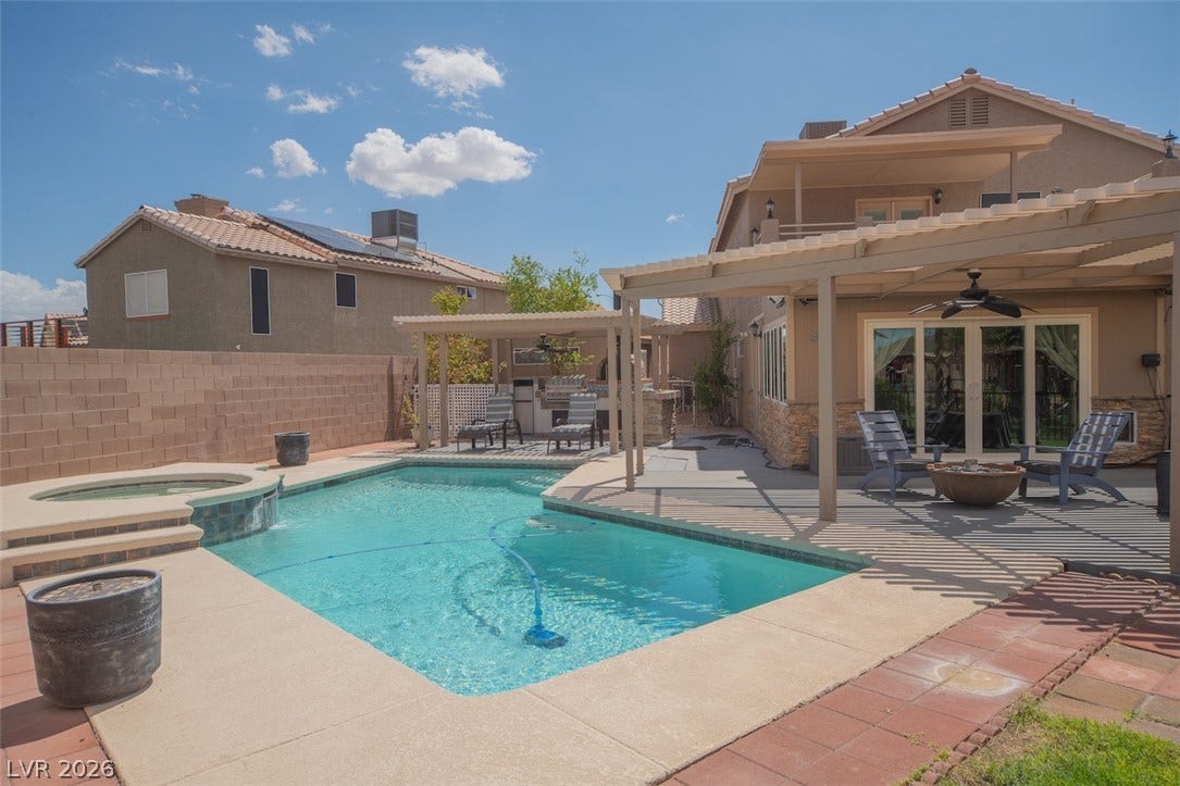 121 Heather Drive, Henderson, NV 89002 An inviting backyard oasis features a shimmering swimming pool paired with a spacious covered patio.