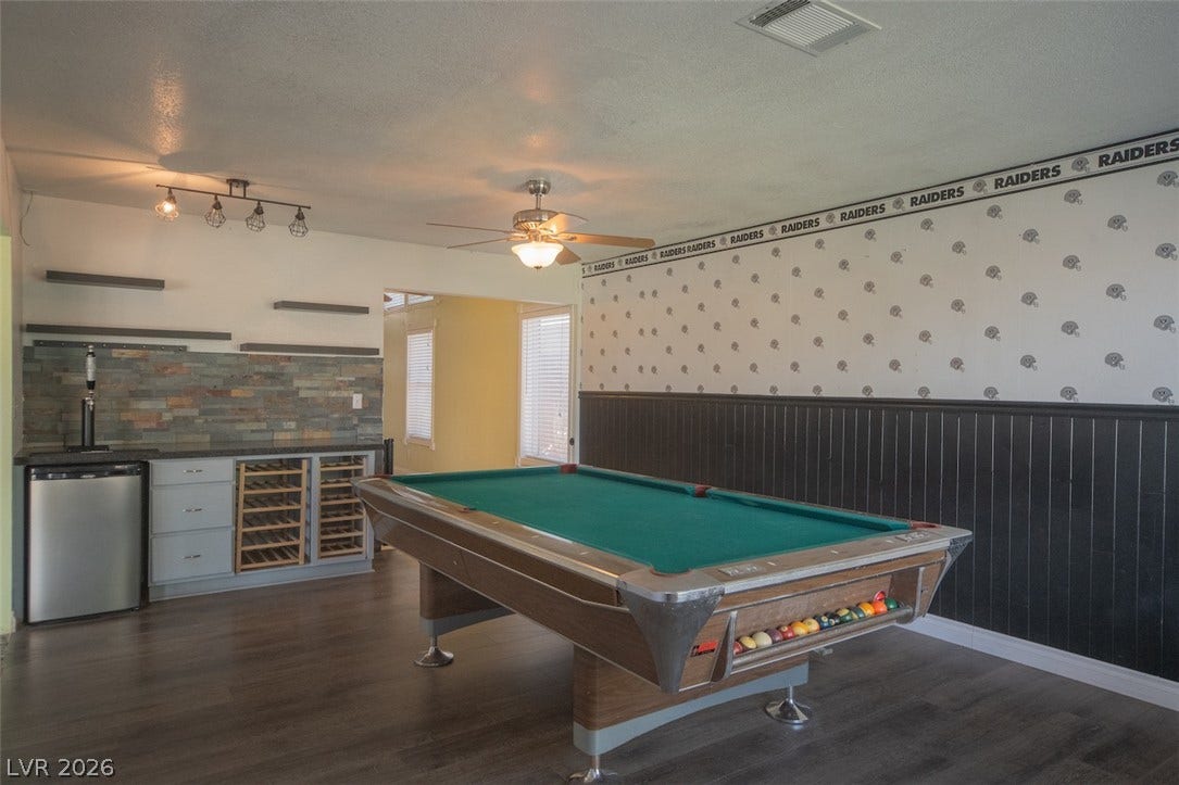 121 Heather Drive, Henderson, NV 89002 A spacious recreation room features rich wood-look flooring and a built-in wet bar setup.