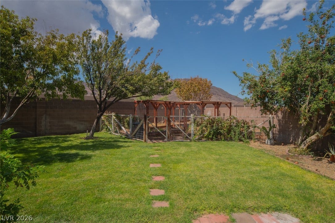 121 Heather Drive, Henderson, NV 89002 A spacious lawn area includes stepping stones and a secure enclosure surrounded by privacy fencing.